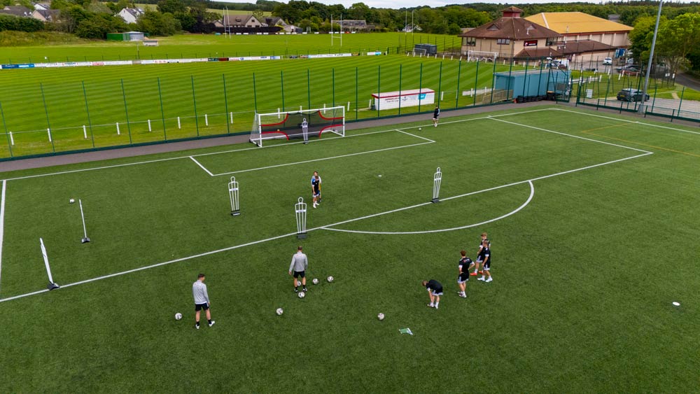 A high-angle view of players lining up to practice shooting penalties at The Meadows Sports Centre