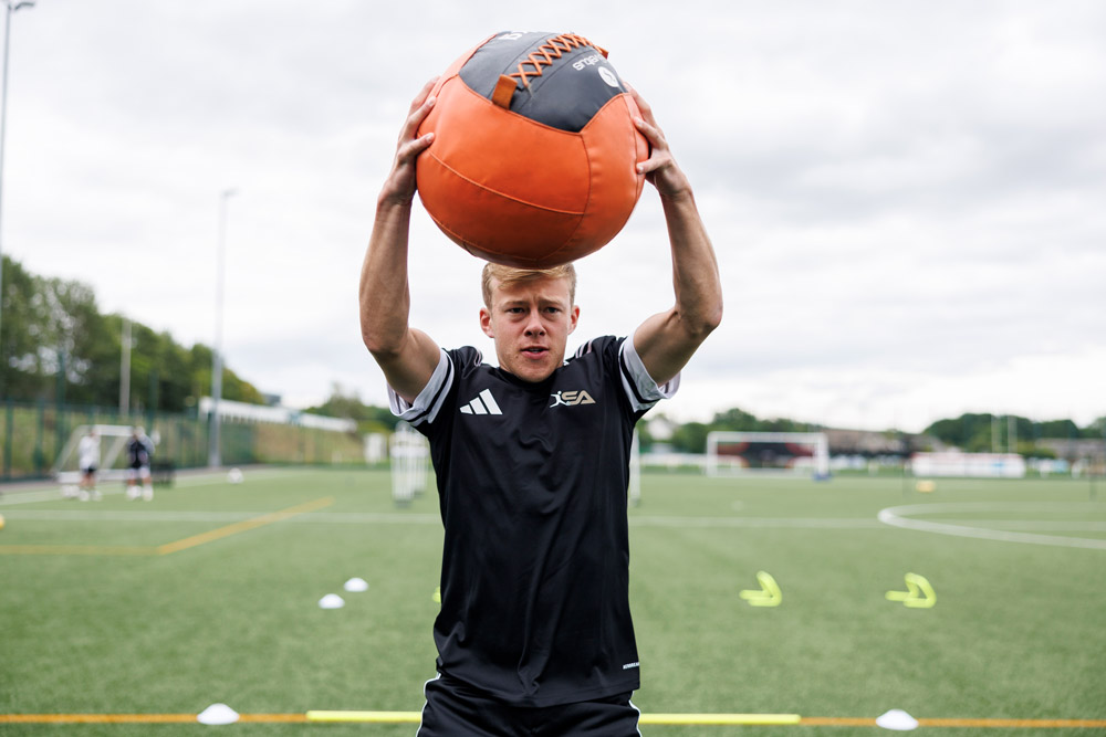Connor Barron warming up on the pitch with a medicine ball.