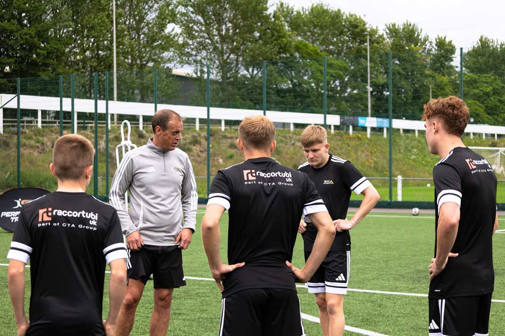 Scott talking to a small group of players after a football training session.